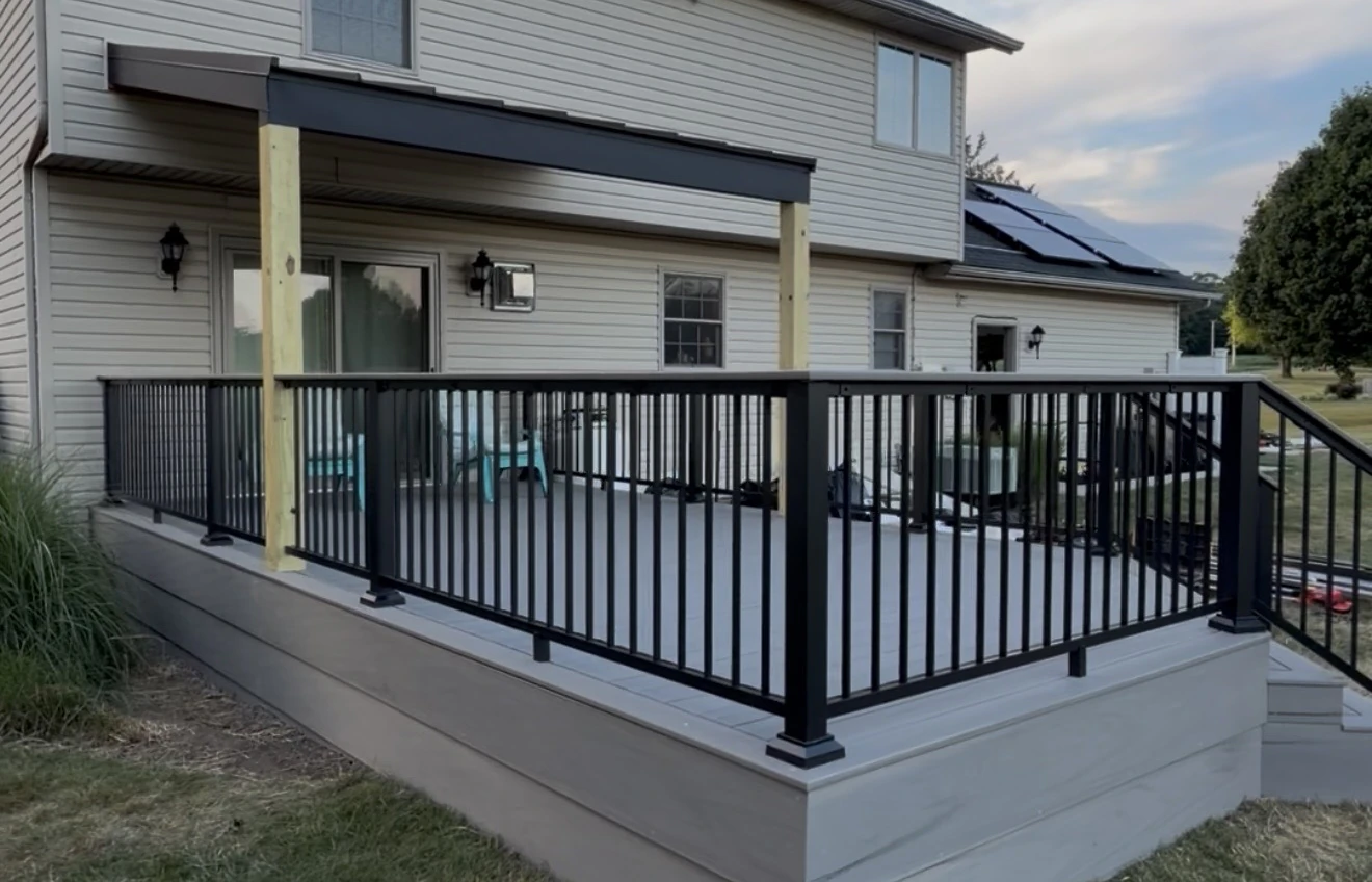 Grey deck with black railings behind a two-storey house