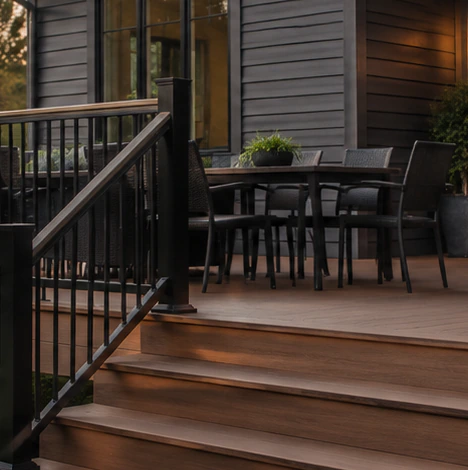 Timber deck with black railings and steps leading to a lawn at dusk